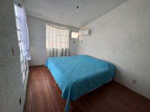 a small bedroom with a blue bed and a window at Refugio de mar y arena in Acapulco