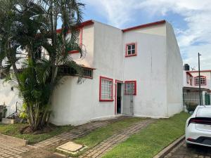 a white house with red windows and a palm tree at Refugio de mar y arena in Acapulco