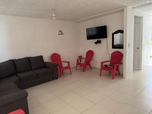 a living room with a couch and red chairs at Refugio de mar y arena in Acapulco