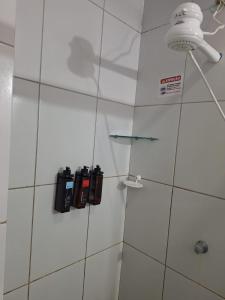 a bathroom with a white tiled wall with a shower at Marcone Lima - Chalés in Barreirinhas