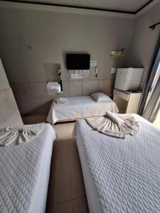 two beds in a small room with a tv at Marcone Lima - Chalés in Barreirinhas