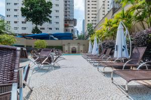 a row of chairs with umbrellas and a pool at Flat Hotel Merc Espaçoso Ibirapuera 4 estrelas com Wi-Fi Recepção 24 horas 3PRI in São Paulo