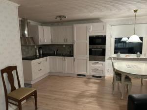 a kitchen with white cabinets and a table and chairs at Kukkolaforsen 160 in Haparanda