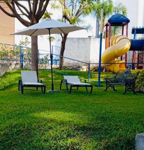 a park with chairs and an umbrella and a slide at Hermoso departamento en Tequesquitengo alberca jacuzzi y acceso al lago in Tequesquitengo