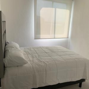a bedroom with a white bed with a window at Hermoso departamento en Tequesquitengo alberca jacuzzi y acceso al lago in Tequesquitengo +20 photos