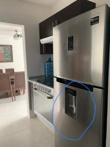 a kitchen with a refrigerator with a blue cord on it at Hermoso departamento en Tequesquitengo alberca jacuzzi y acceso al lago in Tequesquitengo
