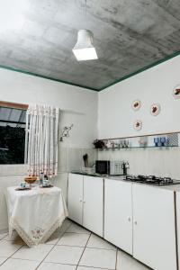 a kitchen with white cabinets and a table in it at Country house, peace comfort & love in Contagem