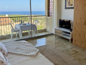 a room with a balcony with a table and a television at Studio proche Calvi in Lumio