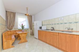 a kitchen with wooden cabinets and a table and a sink at Willa Irena in Karwia