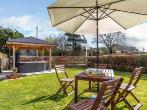 a table and chairs with an umbrella in a yard at 2 Bed in Launceston oc-41992 in Saint Giles on the Heath +8 photos
