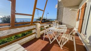 a balcony with a table and chairs and the ocean at S'Archittu Sunset House in S'archittu Cuglieri