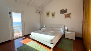 a bedroom with a white bed and a large window at S'Archittu Sunset House in S'archittu Cuglieri