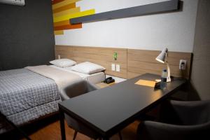 a hotel room with two beds and a desk with a lamp at Hotel 10 Itajai/Navegantes in Itajaí +62 photos