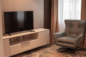 a living room with a television and a chair at Atrium Hotel in Vulcan