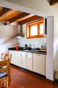 a kitchen with white cabinets and a sink and a table at Casa do Olival in Macedo de Cavaleiros