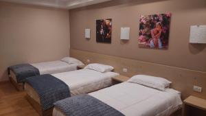three beds in a room with paintings on the wall at Hotel Green in Tirana