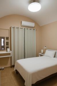 a bedroom with a white bed and a air conditioner at Casa Paraíso in Ixtapa