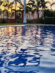a pool of water with palm trees and a building at Casa Paraíso in Ixtapa +7 photos