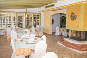 a restaurant with white tables and chairs and a fireplace at Hotel Don Manuel in Ronda
