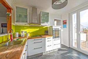 a kitchen with white cabinets and yellow tiles at Maison Charme, Jardin, Brest in Le Relecq-Kerhuon