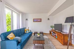a living room with a blue couch and a flat screen tv at Maison Charme, Jardin, Brest in Le Relecq-Kerhuon