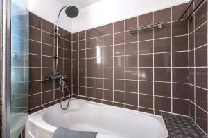 a bath tub in a bathroom with brown tiles at Maison Charme, Jardin, Brest in Le Relecq-Kerhuon +6 photos