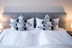 a bed with white sheets and pillows at PuraStays - studio 2 in Herzogenaurach