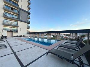 a balcony with chairs and a swimming pool on a building at Spacious Central Apartment, Pool & Gym, Group Friendly in Hermosillo