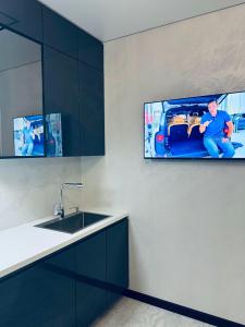 a kitchen with a sink and a tv on the wall at Перлина Люкс in Khmelnytskyi