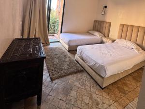 a bedroom with two beds and a table and a window at Al ATLAS résidence in Marrakesh +15 photos