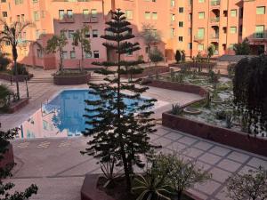 a pine tree in a courtyard next to a swimming pool at Al ATLAS résidence in Marrakesh