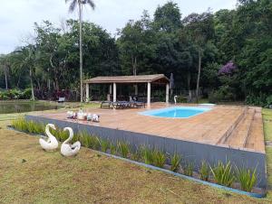 a pool with a wooden deck and a gazebo at Chácara Paraíso in Itupeva