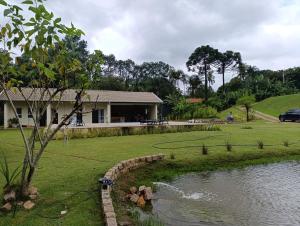 a house with a pond in front of a house at Chácara Paraíso in Itupeva