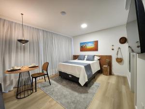 a bedroom with a bed and a table in a room at Loft próximo à Oktoberfest Blumenau in Blumenau