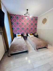 a bedroom with two beds and a colorful wall at Apartamenty Brzeska 10 in Warsaw