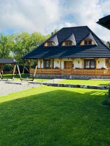 a house with a gambrel roof and a playground at Casa Moroșanului Vișeu de Sus in Vişeu de Sus