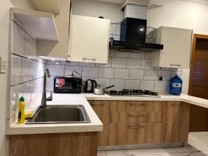 a kitchen with a sink and a microwave at Prime Stays Rezidor in Rawalpindi