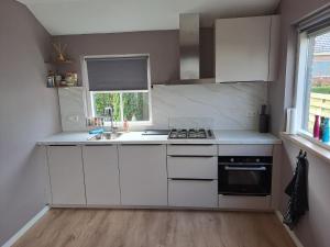 a kitchen with white cabinets and a sink and a window at Vakantiehuis in Oosterwolde
