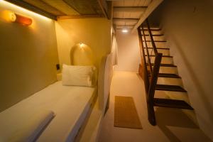 a small room with a bed and a staircase at Hostel Tainha Caraíva in Caraíva
