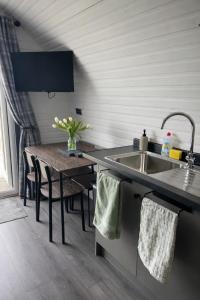 a kitchen with a sink and a wooden table at Millfield Glamping Pods - Heatherhouse in Orkney