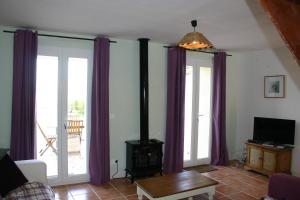 sala de estar con cortinas moradas y estufa de leña en Jj French Gites, en Pécharic-et-le-Py