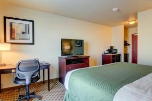 a hotel room with a bed and a desk and a television at Cobblestone Inn & Suites - Carrington in Carrington