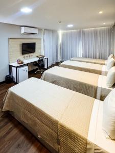 a hotel room with two beds and a desk at Citi Executivo Hotel in Parnaíba