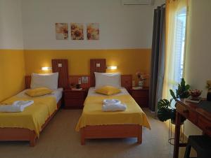 two beds in a room with yellow walls at on the STRIP-Studio 2 in Kavos