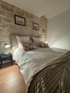 a large bed in a bedroom with a stone wall at Chez Marie & Nico in Aigues-Mortes
