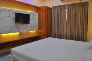 a bedroom with a white bed and a television at Hotel Shivar in Kalam