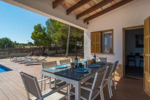 a dining table and chairs on a patio at Villa Anglesos in Can Picafort