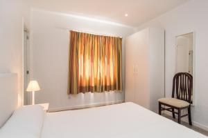 a bedroom with a bed and a chair and a window at Villa Anglesos in Can Picafort