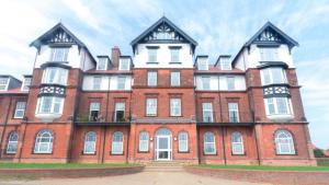 a large red brick building with white windows at Grand Norfolk in Mundesley