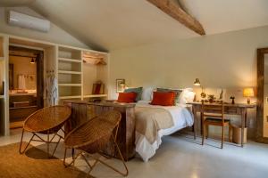 a bedroom with a bed and a desk and chairs at Na Praça Hotel in Trancoso